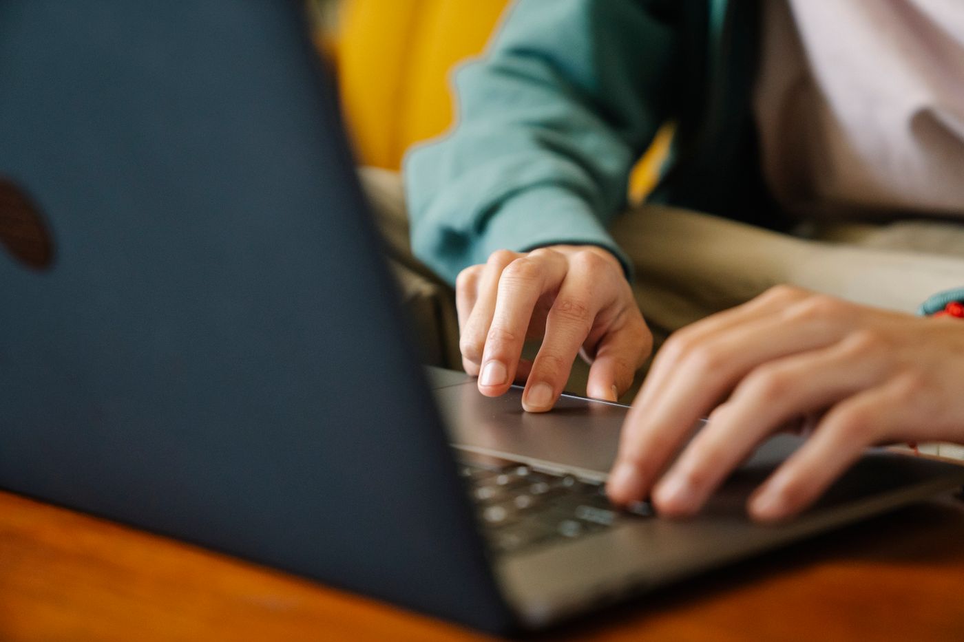 Hands typing on a laptop at a wooden table