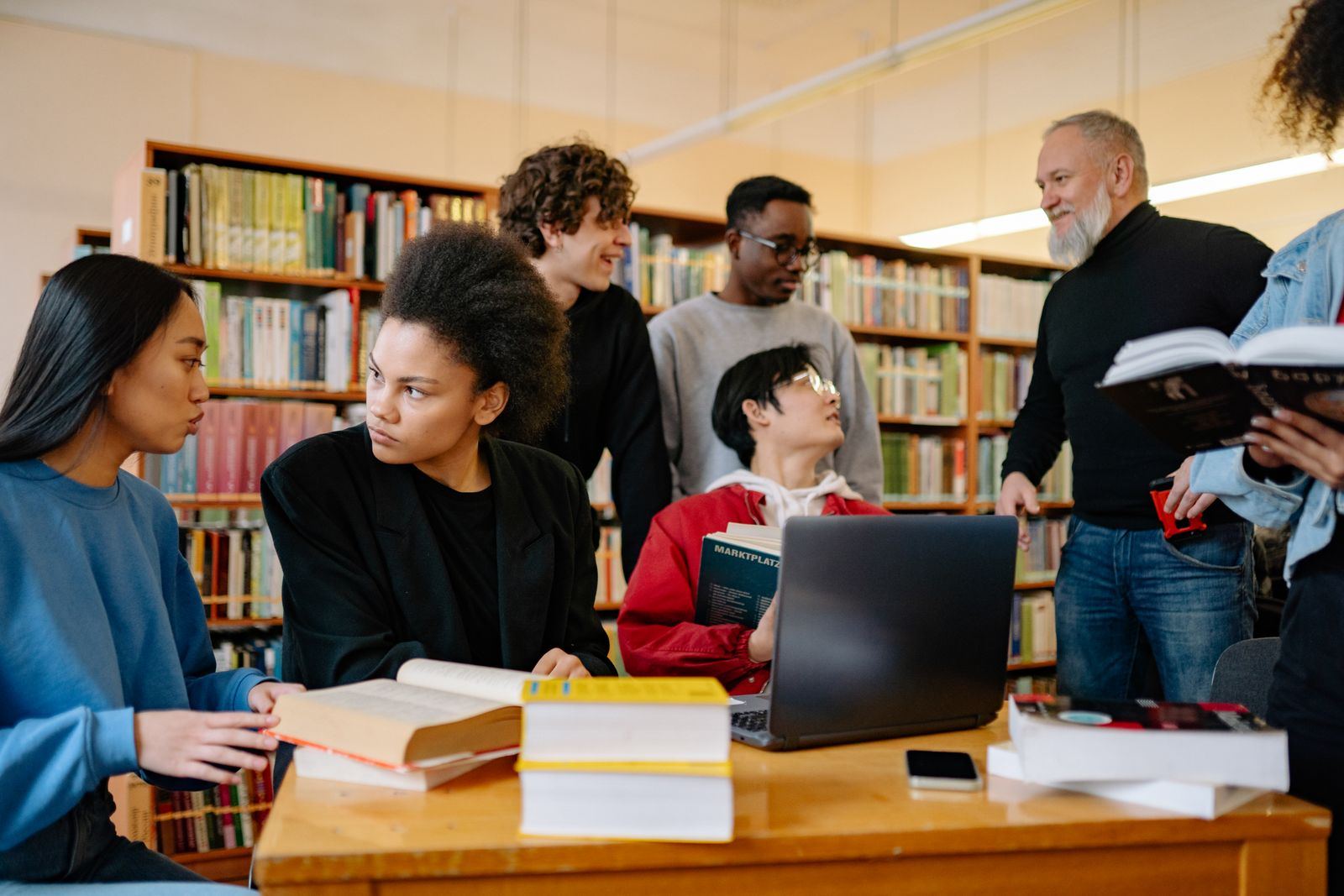 Students talking around a laptop in a library